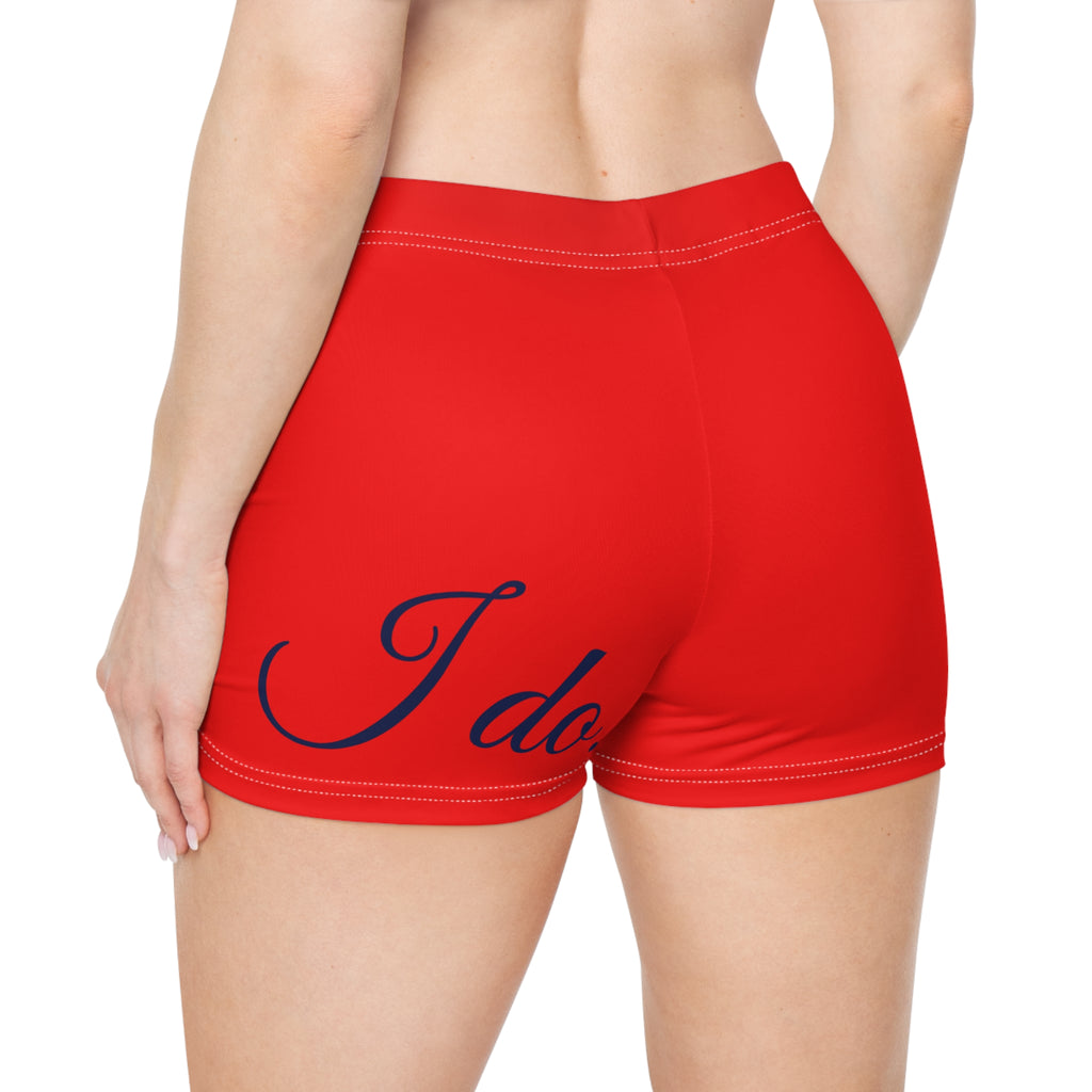 Red athletic shorts with white contrast stitching and a navy blue script graphic reading 'I do' on the back, shown on a model from behind against a white background.